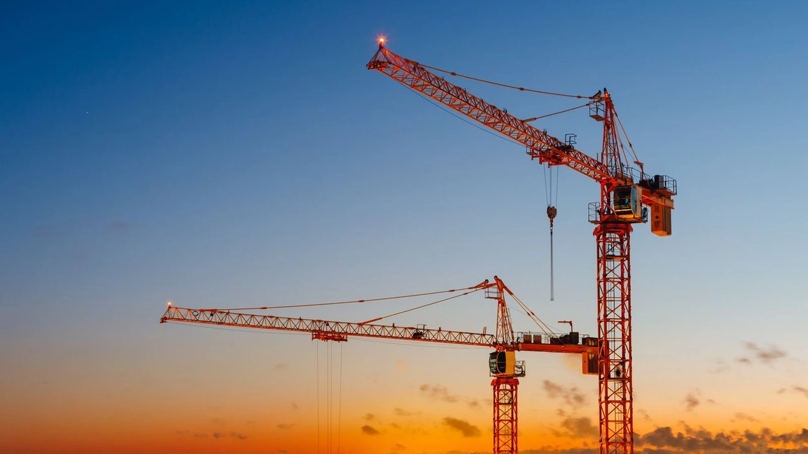 Real tower cranes working on a construction skyline at sunset